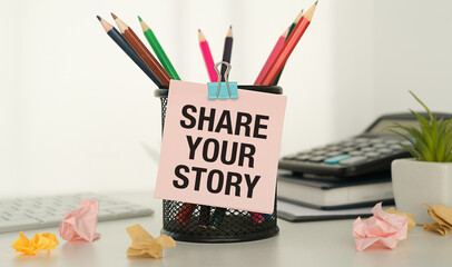 Share your story written on pink sticker on office background, business and social media concept
