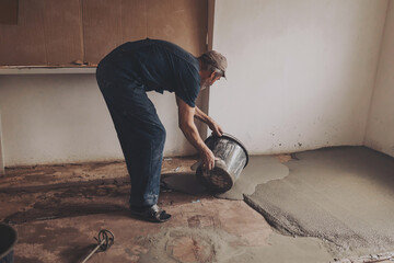 Worker pouring concrete on the floor.  apartment during renovation.
