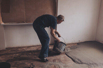 Worker pouring concrete on the floor.  apartment during renovation.