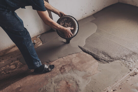 Worker pouring concrete on the floor.  apartment during renovation.