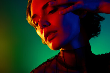 Close up photo of woman with closed eyes touch face under neon light isolated colorful background