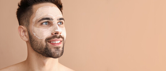 Handsome man with clay mask on his face against color background