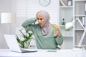 Deceived woman in hijab trying to make an online purchase, business woman holding bank credit card,...