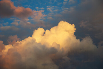 A vibrant evening sky showcases billowing clouds illuminated by the setting sun, creating a serene...