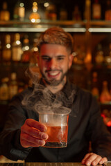 Young elegant barman working behind a bar counter mixing drinks