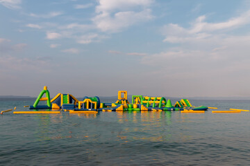 Inflatable bouncing castle drifting on waves of Aegean Sea. Aquapark with attractions in the sea....