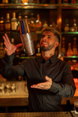 Young elegant barman working behind a bar counter mixing drinks