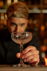 Young elegant barman working behind a bar counter mixing drinks