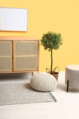 Interior of modern living room with dresser, houseplant and poufs