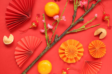 Sakura branch with fortune cookies, mandarins and Chinese symbols on red background. New Year...