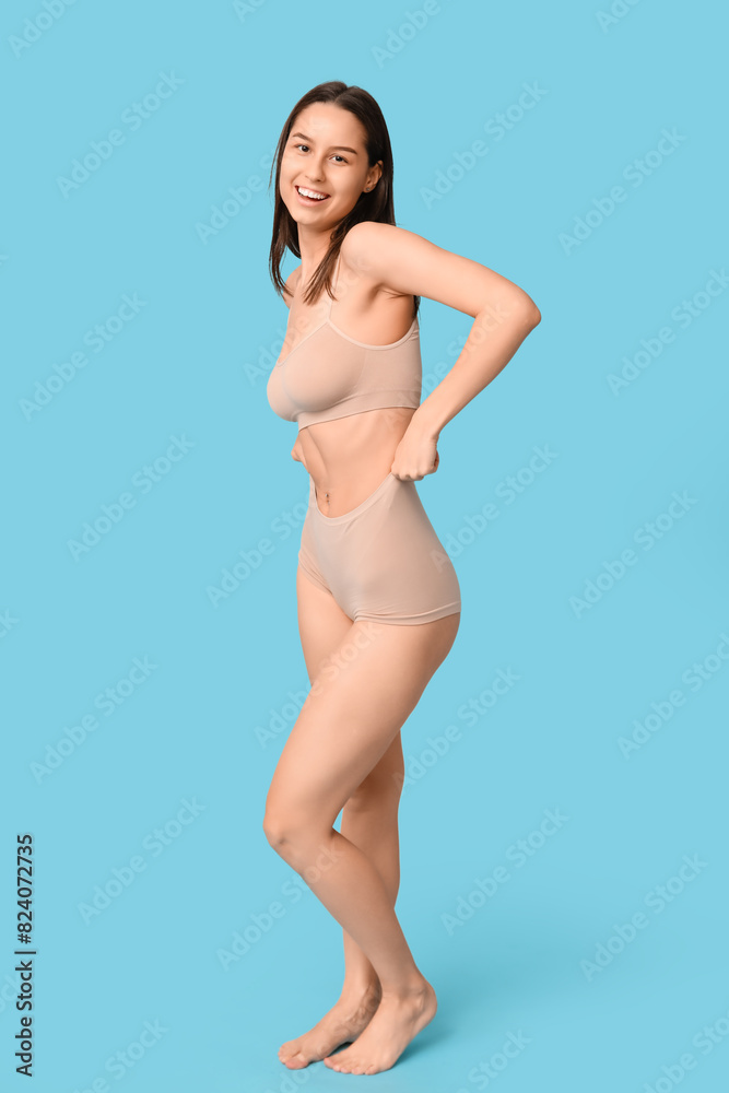 Poster Beautiful young woman in nude underwear on blue background