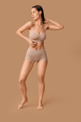 Obraz premium Beautiful young woman in underwear on beige background