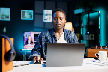 Young african american freelancer working at home on her digital laptop, reviewing documents. Black...