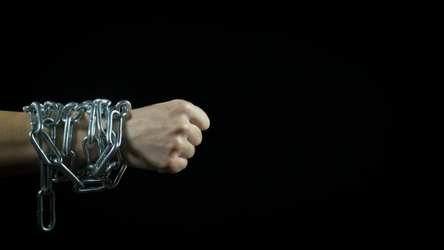 Chained hand with thumb up. A view of chained hands show the thumb up on the black background.