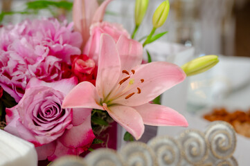 A beautiful bouquet of flowers placed on a table. The bouquet consists of pink roses, a pink lily,...