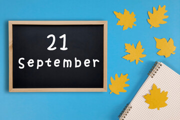September 21 written in chalk on black board. Calendar date 21th of September on chalkboard on blue...