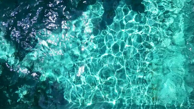 Shooting from a drone, blue water in an outdoor pool with reflections of light.