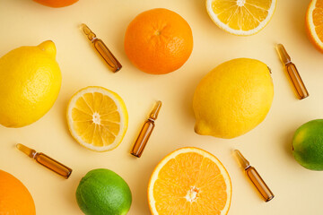 Composition with ampules of vitamin C and fresh citrus fruits on color background
