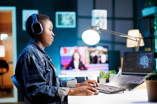 African American woman working on laptop, using AI to develop futuristic software system. Black female individual with her personal computer, showing her skill in programming and cyber security.