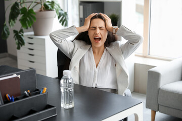 Young woman suffering from strong headache sitting in office