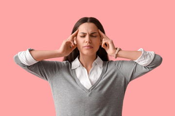 Young woman suffering from headache on pink background