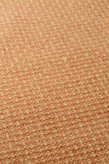 Orange-peach woven upholstery fabric texture. Close-up detail photograph.