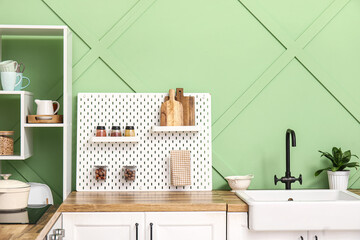 Pegboard, sink and houseplant in kitchen near green wall