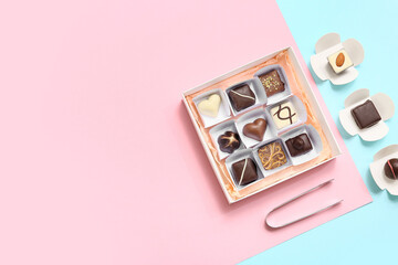 Box with candies and kitchen tongs on color background