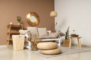 Interior of stylish living room with comfortable sofa and poufs, blurred view
