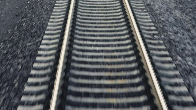 Railroad line with sleepers on gravel ground at sunset time. Motion along railway view from train cabin. Transport system of trains route closeup