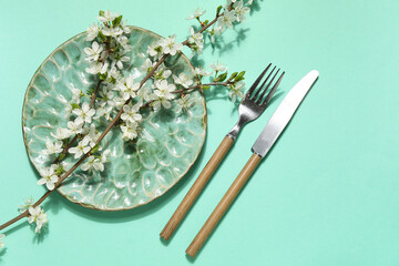 Beautiful table setting with blossoming branches on turquoise background
