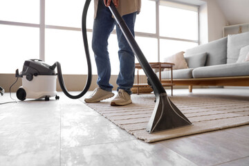 Young man cleaning carpet at home, closeup