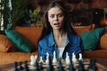 Strategic thinking Woman with flowing hair playing chess on a couch, wind blowing through the room