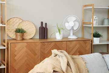 Modern electric fan with decor on commode at home