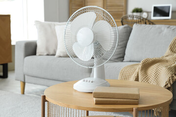 Interior of light living room with modern electric fan on coffee table, closeup