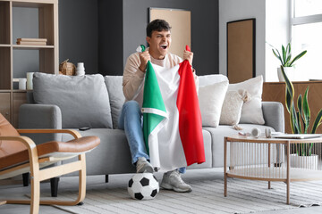 Young man with flag of Italy watching football game on TV at home
