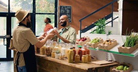 Local farmer presents ripe vegetables to client in zero waste eco store, selling freshly harvested...