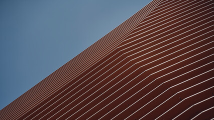 Fachada en tonos naranja y tierra en ciudad contemporánea con cielo, y formas geométricas