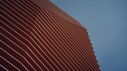 Fachada en tonos naranja y tierra en ciudad contemporánea con cielo, y formas geométricas