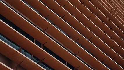 Fachada de edificio en metal naranja y cálido en líneas diagonales