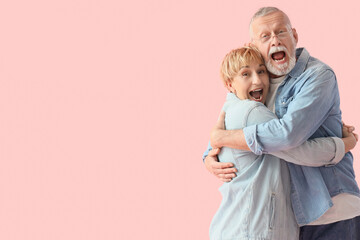 Mature couple hugging with falling money on pink background