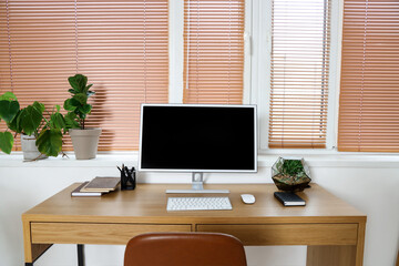 Workplace with computer monitor and green houseplants near window in office