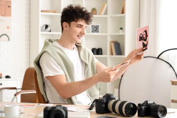 Professional happy male photographer with modern cameras choosing photos in studio
