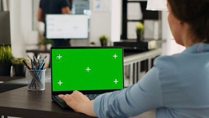 Business person using chromakey laptop with greenscreen template in startup office. Company...