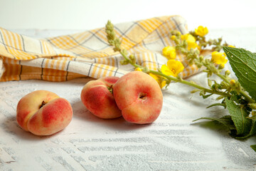 Three saturn peaches or flat peach on white wooden background..