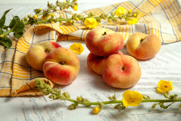 Several whole saturn peaches or flat peach on white wooden background..