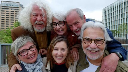 Portrait of happy diverse senior friends standing together at city. Elderly adult people smiling at camera enjoying free time on vacation.