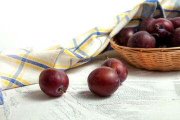 Purple plums on white wooden background. .