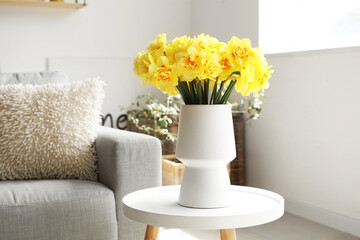 Vase with beautiful daffodil flowers in living room