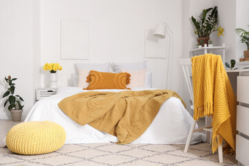 Interior of light bedroom with cozy bed and yellow narcissus flowers